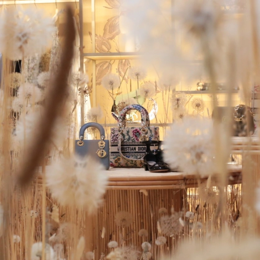 Spotlighted woman's hand bags display surrounded by botanical elements