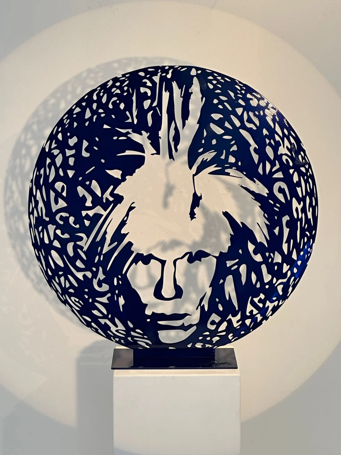 Blue painted steel portrait sculpture on display plinth